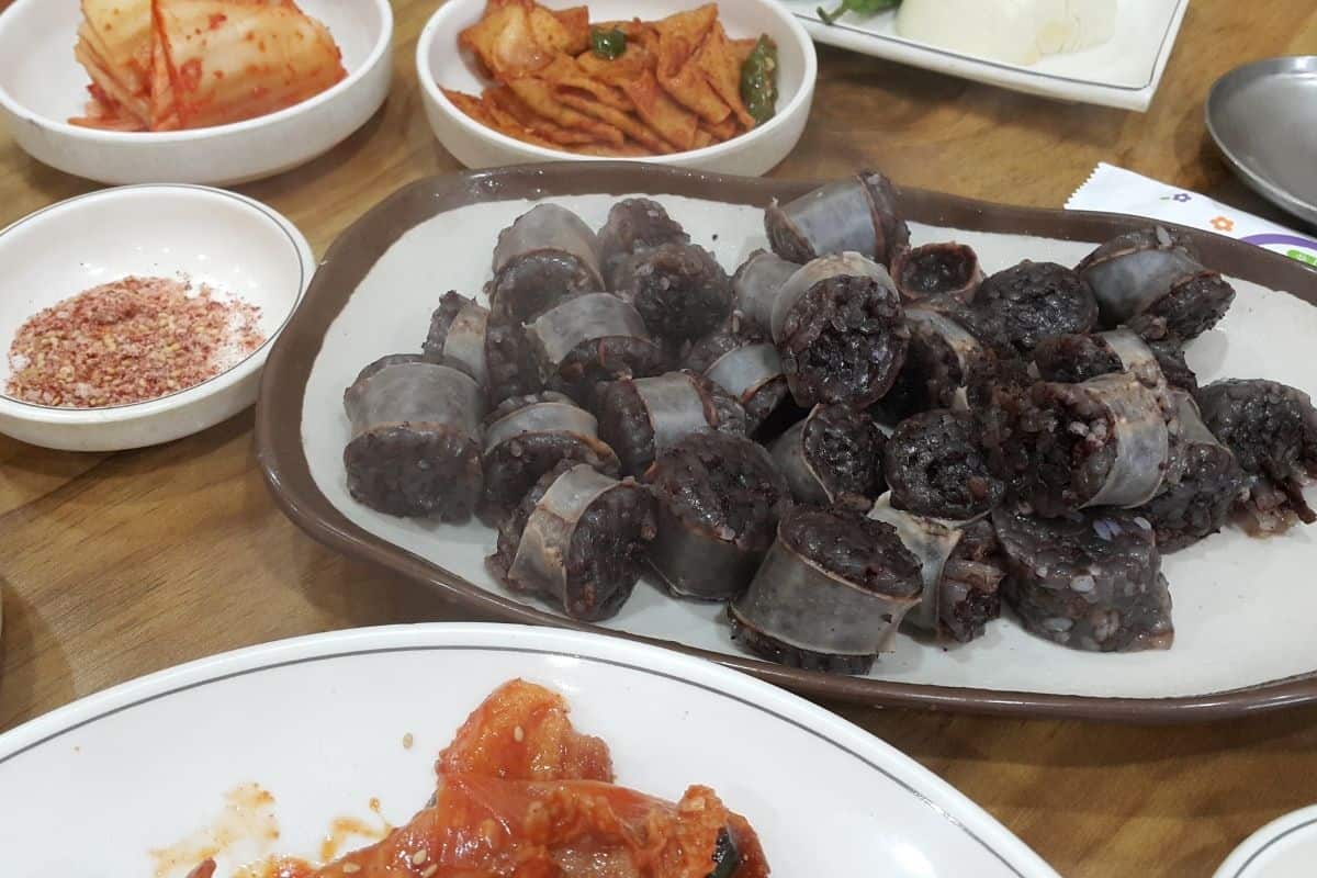 large plate of Korean blood sausage with assorted side dishes.