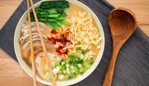 Asian ramen noodle pork bone based soup with pork chashu on cutting board background.