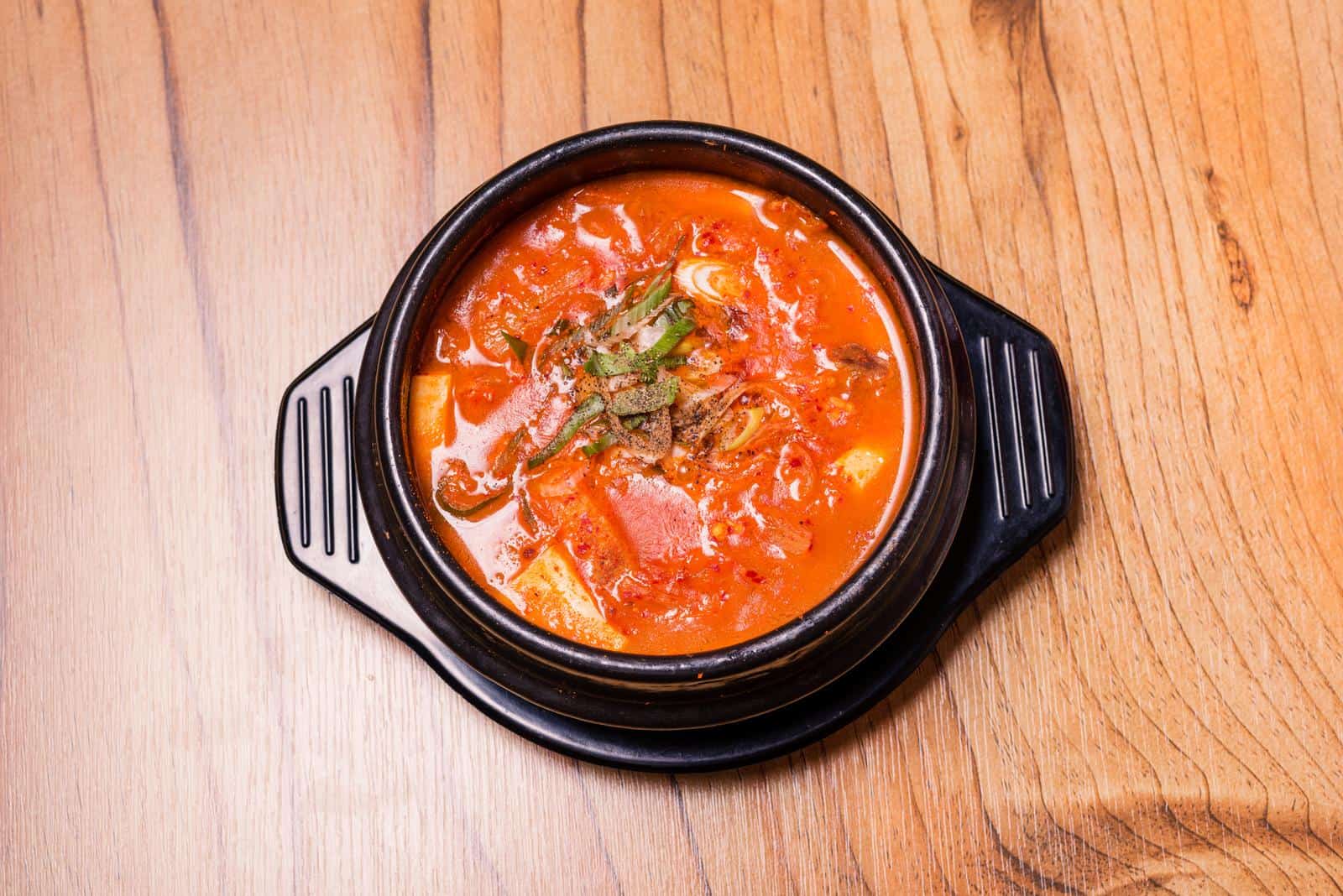 Kimchi soup in hot black iron pot, Korean traditional Kimchi Jjigae soup in bowl in the restaurant, Japanese hot pot food.