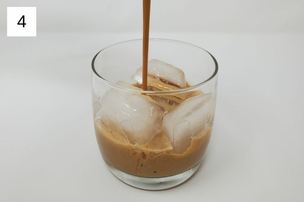 pouring the yuzu coffee mixture into a glass with ice