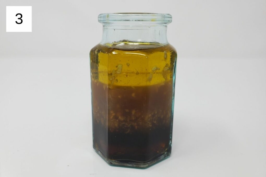 a glass container filled with oil, yuzu juice, maple syrup, coconut aminos, and ginger