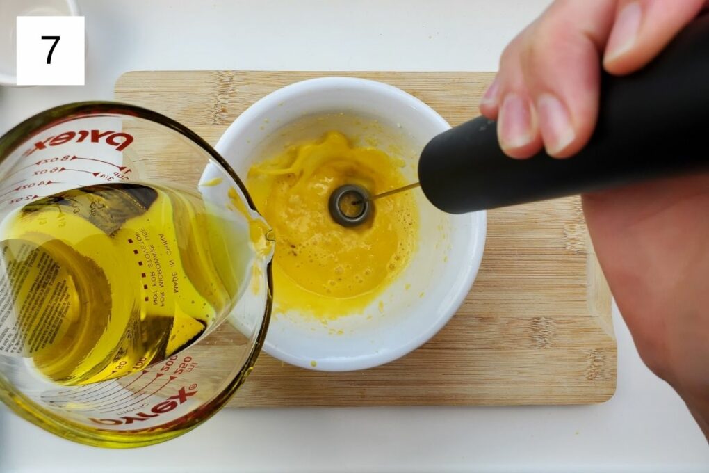 pouring oil into a mixture of yuzu juice, garlic, salt, and egg yolk