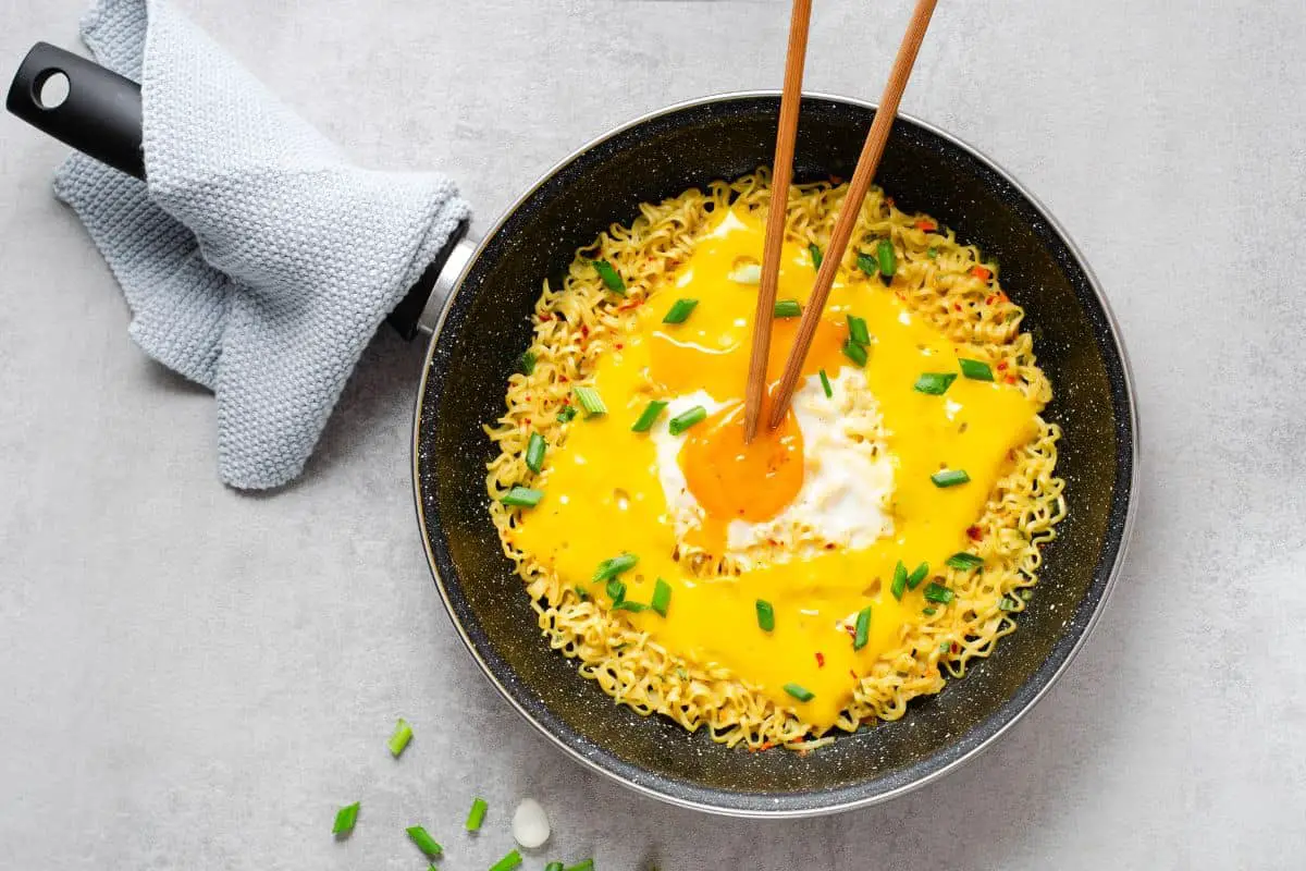 Cheese ramen with egg in a pan.