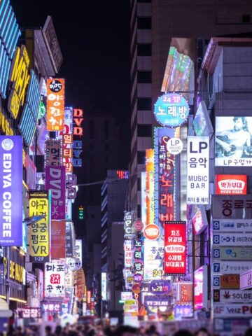 A busy street in Myeongdong with many store signages at night.