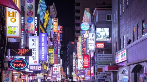 A busy street in Myeongdong with many store signages at night.