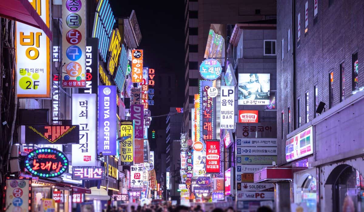 A busy street in Myeongdong with many store signages at night. 