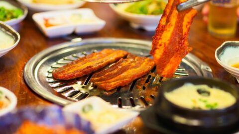 A table with a Korean barbecue grill and different side dishes.