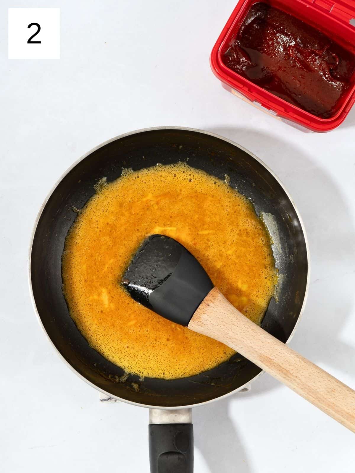 Gochujang and scrambled eggs mixed together in a heated pan.