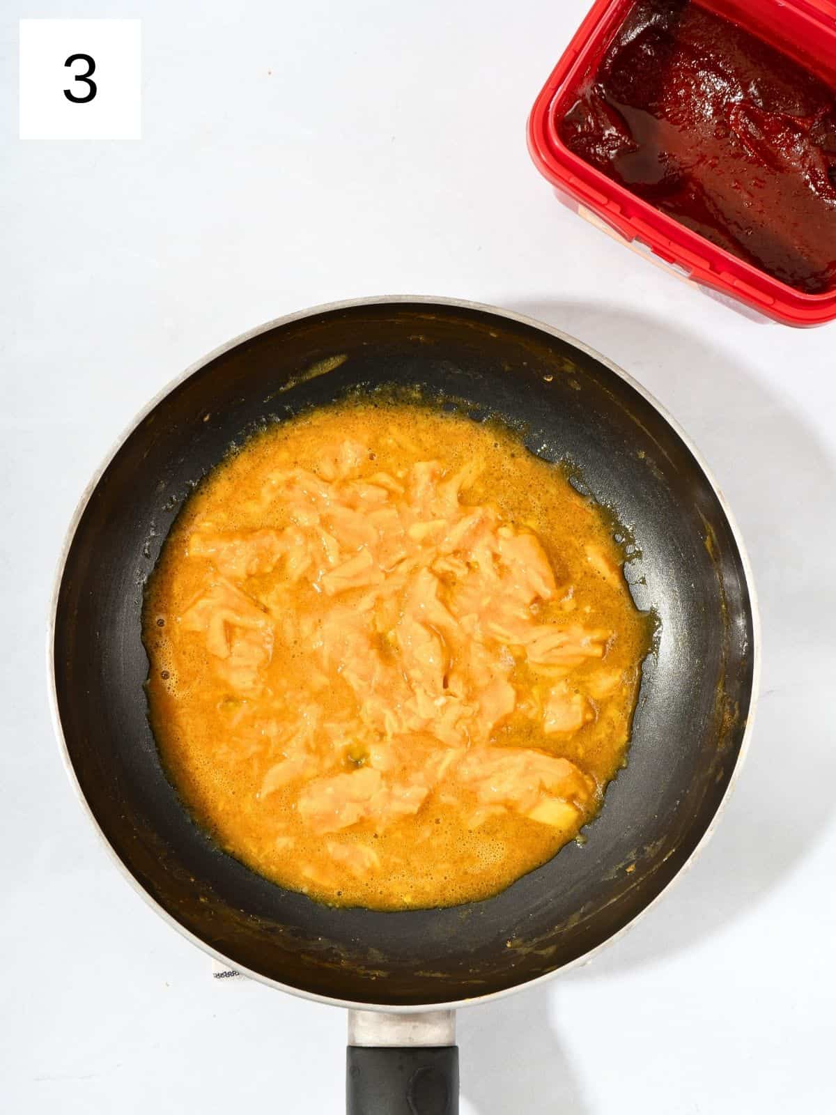 Scrambled eggs cooking in a non-stick pan, with soft, fluffy curds forming.