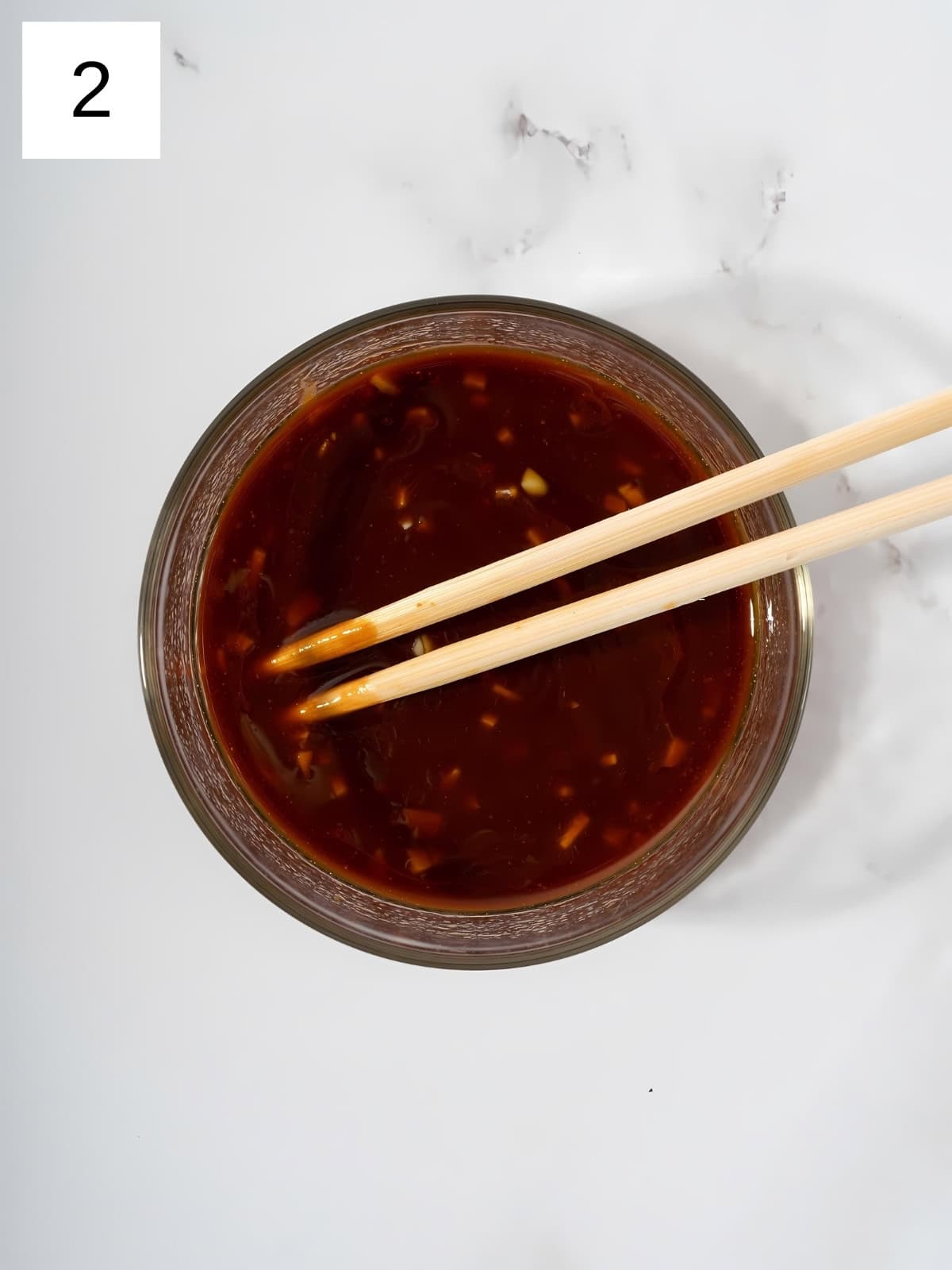 Gochujang mixture being whisked with a chopstick in a bowl.