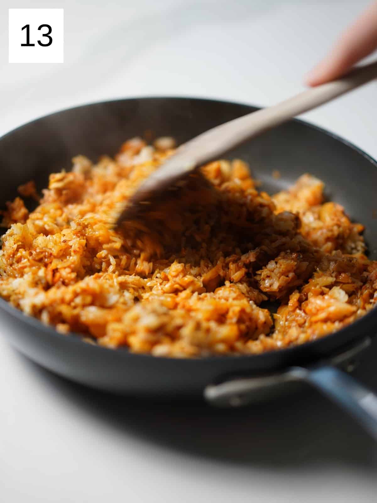 Kimchi fried rice being stirred in a pan. 