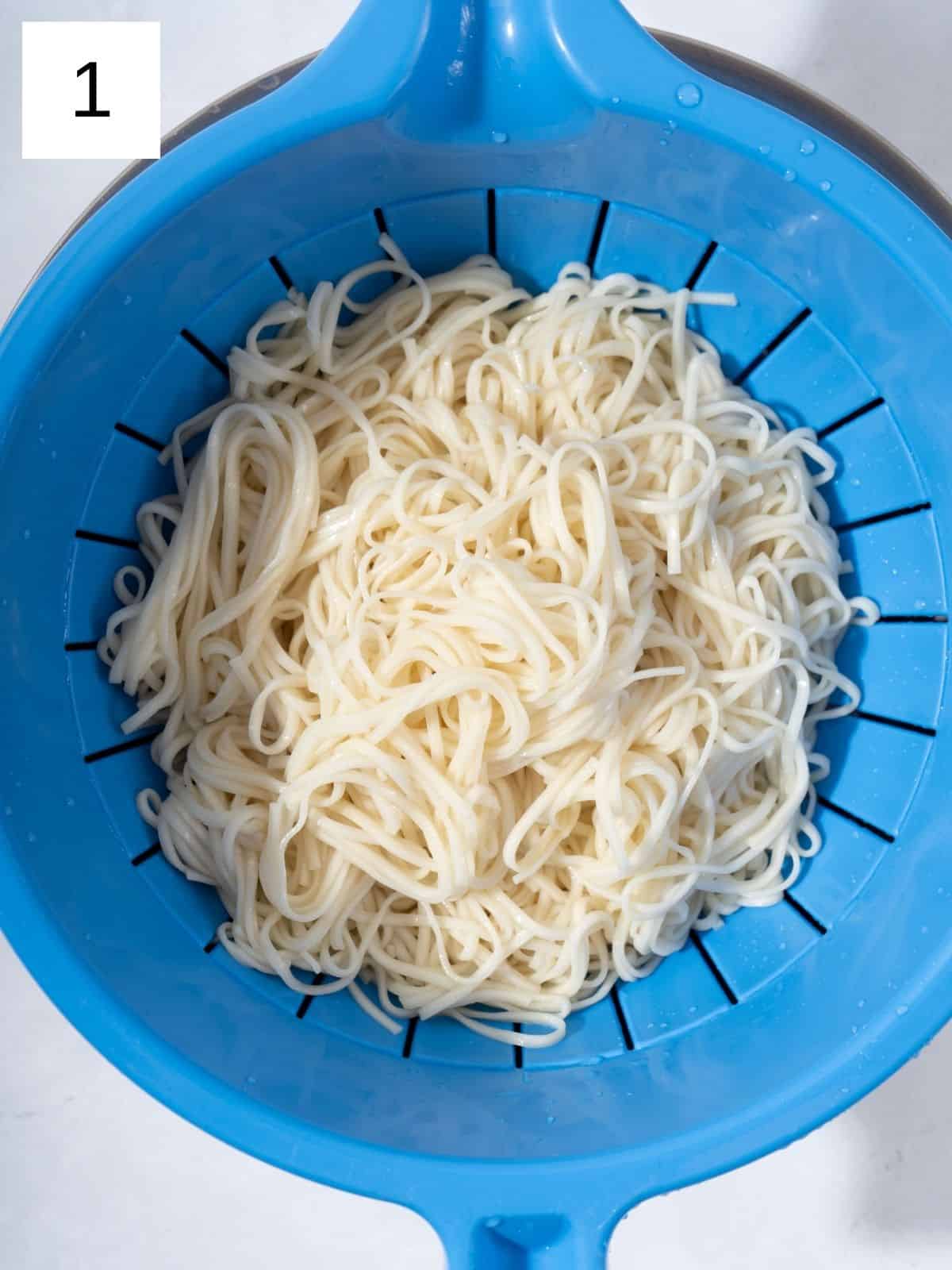Cooked dry noodles being strained.