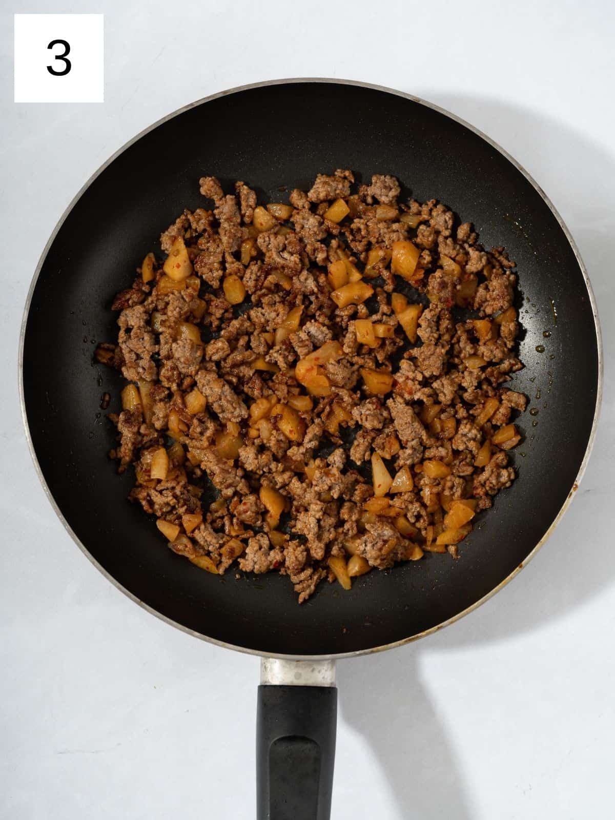 Kimchi and cooked ground meat in a pan.