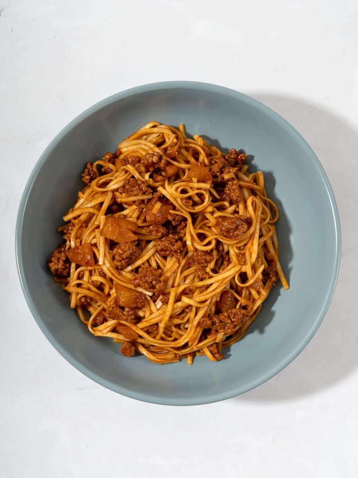 A bowl of kimchi noodles mixed with ground meat and kimchi.