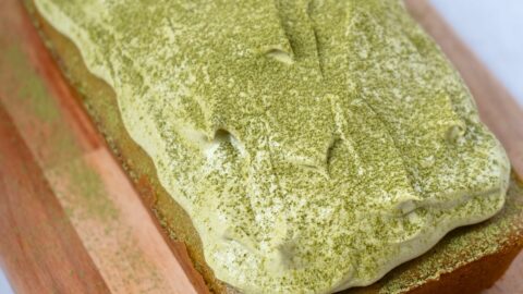 A matcha cake topped with matcha frosting and sprinkled with matcha powder.