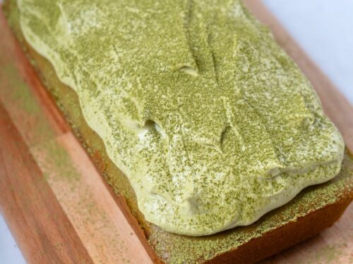 A matcha cake topped with matcha frosting and sprinkled with matcha powder.
