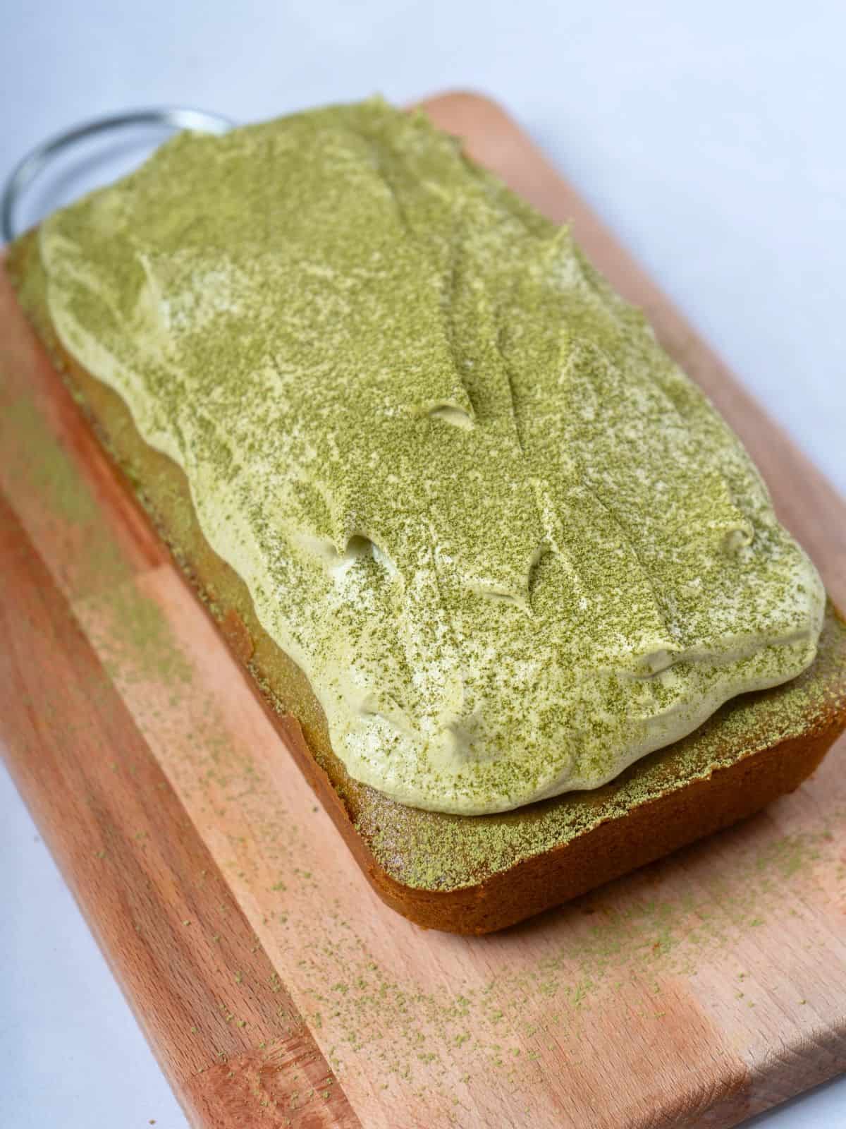 A matcha cake topped with matcha frosting and sprinkled with matcha powder.