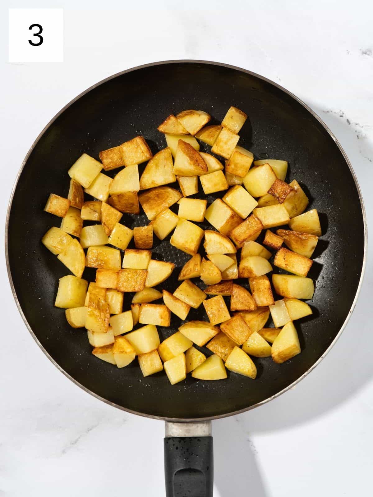 Potato cuts being fried on a pan.