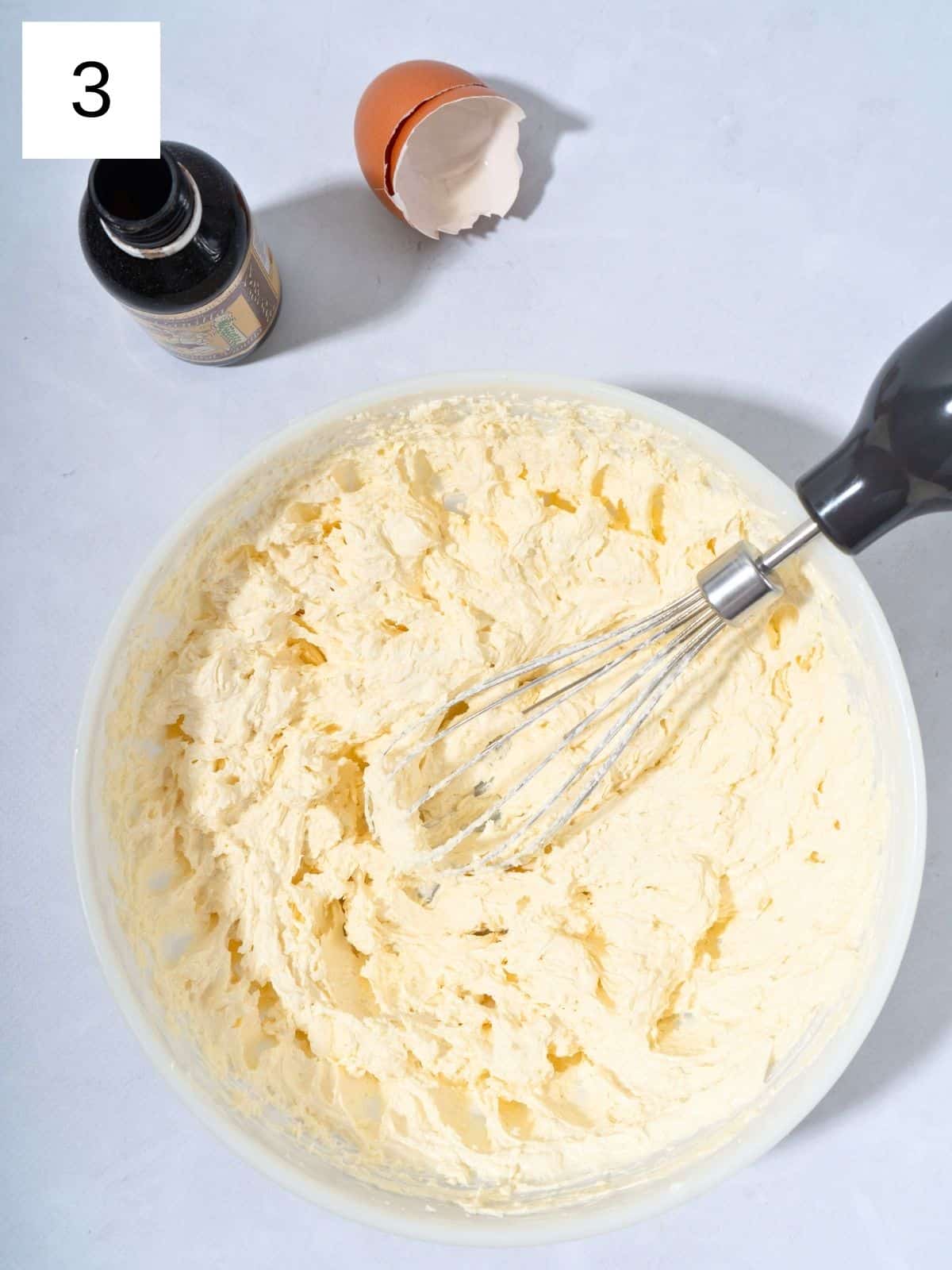 A bowl of whisked dough mixture with added egg and vanilla extract.