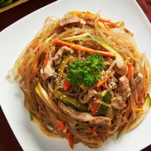 A plate of japchae with side dishes.