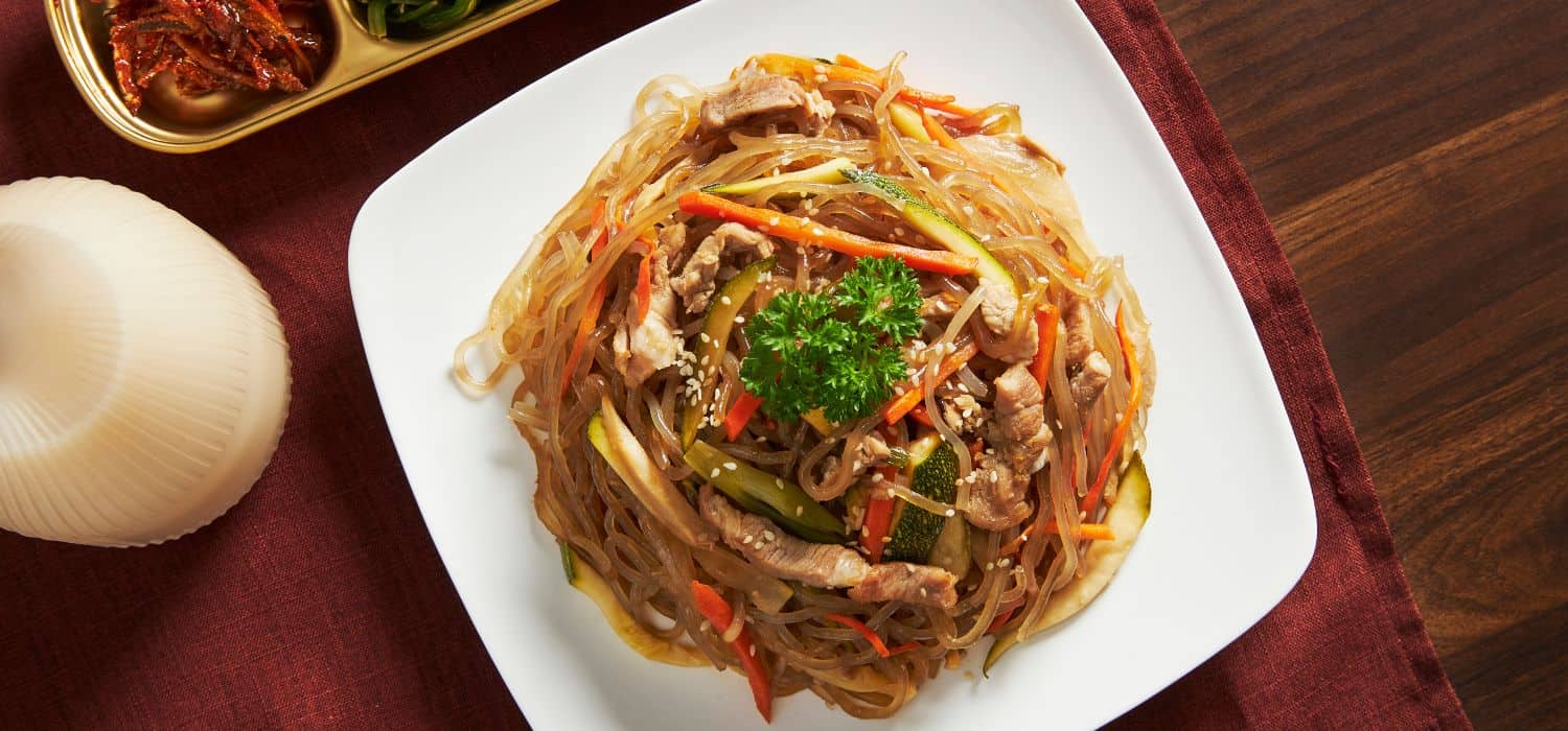 A plate of japchae with side dishes.