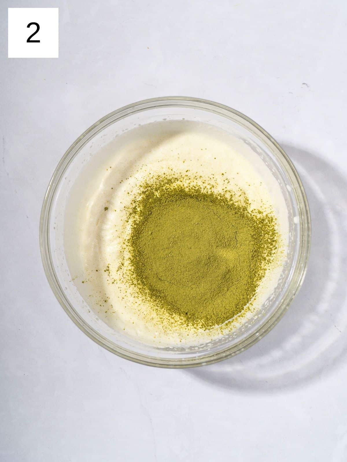 A bowl filled with whipped heavy cream and matcha powder.