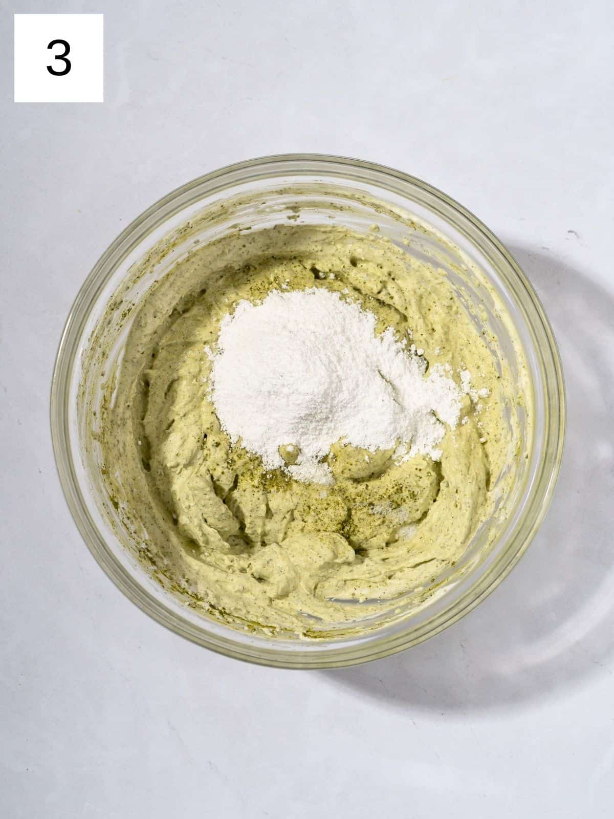 A bowl filled with whipped mixture of matcha powder and heavy cream, topped with powdered sugar.