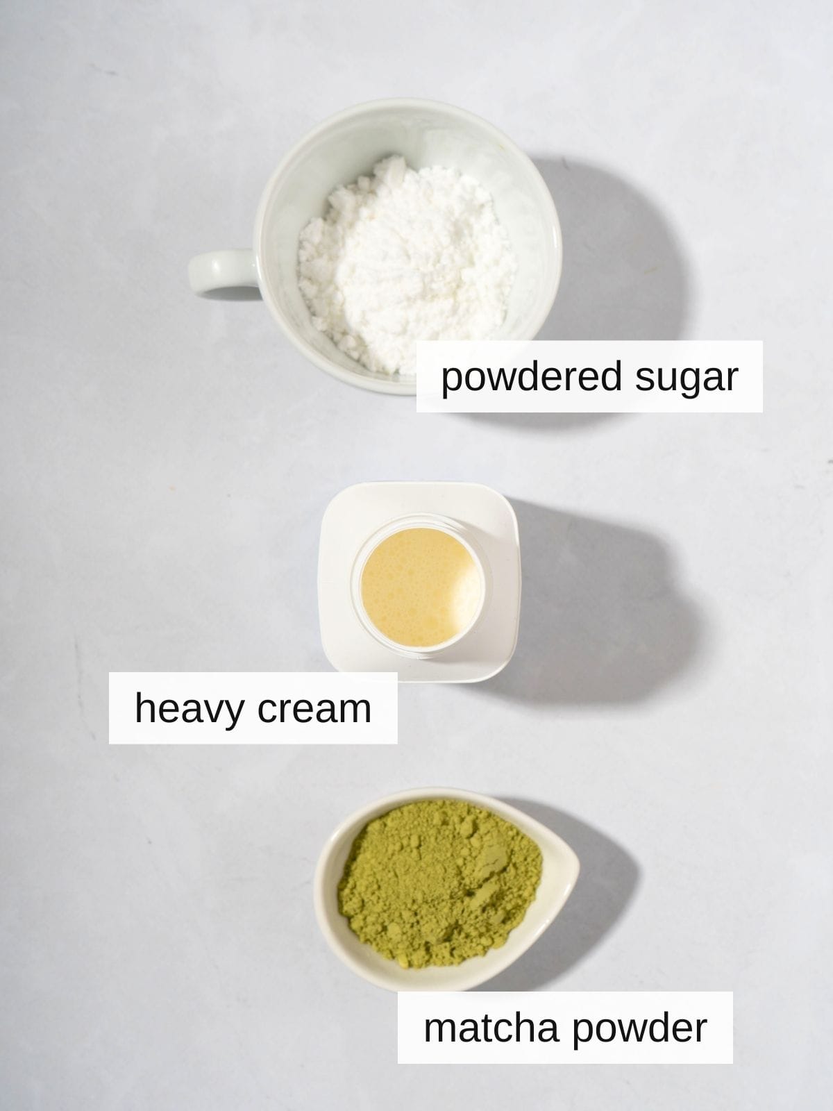 Ingredients for matcha whipped cream, including powdered sugar, heavy cream, and matcha powder.