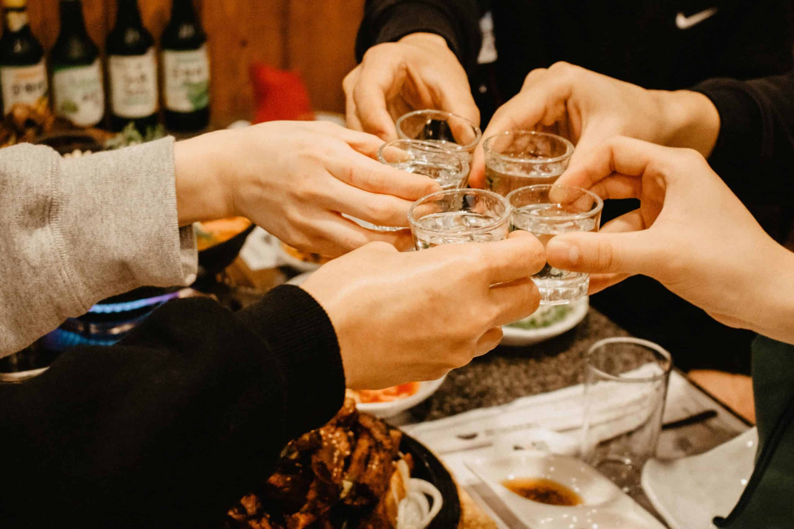 People gathering over a meal, drinking soju.