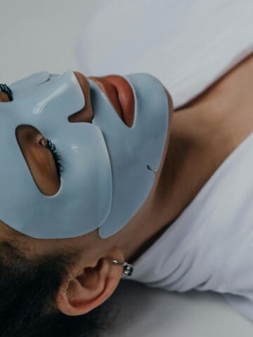 Person applying sheet mask on the face.