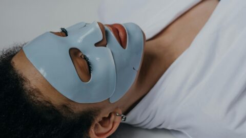 Person applying sheet mask on the face.