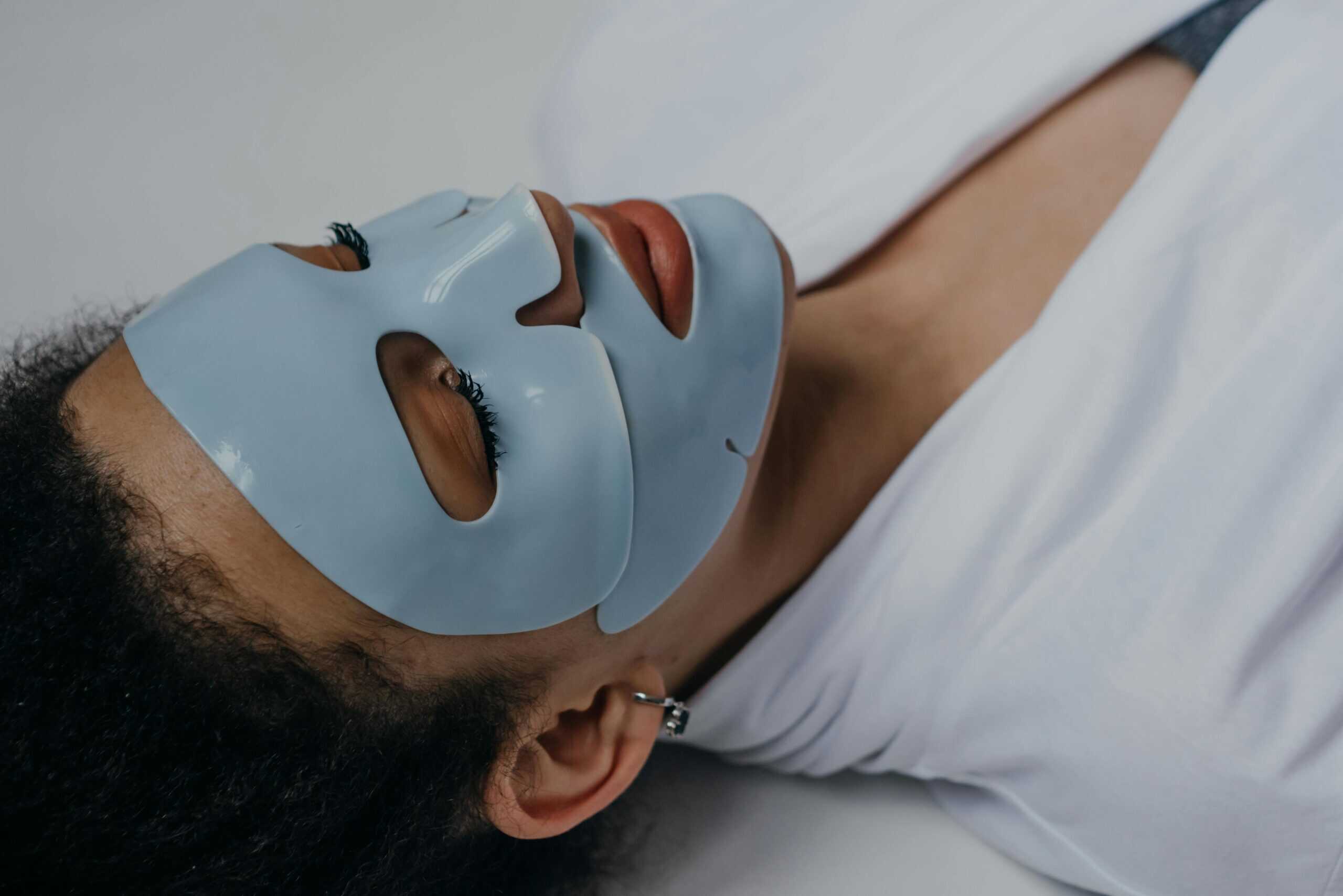 Person applying sheet mask on the face.