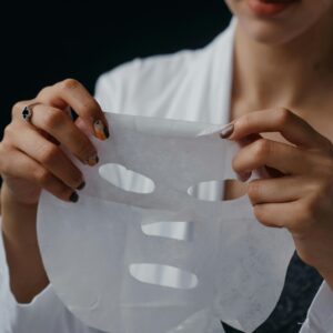 Person putting on sheet mask.