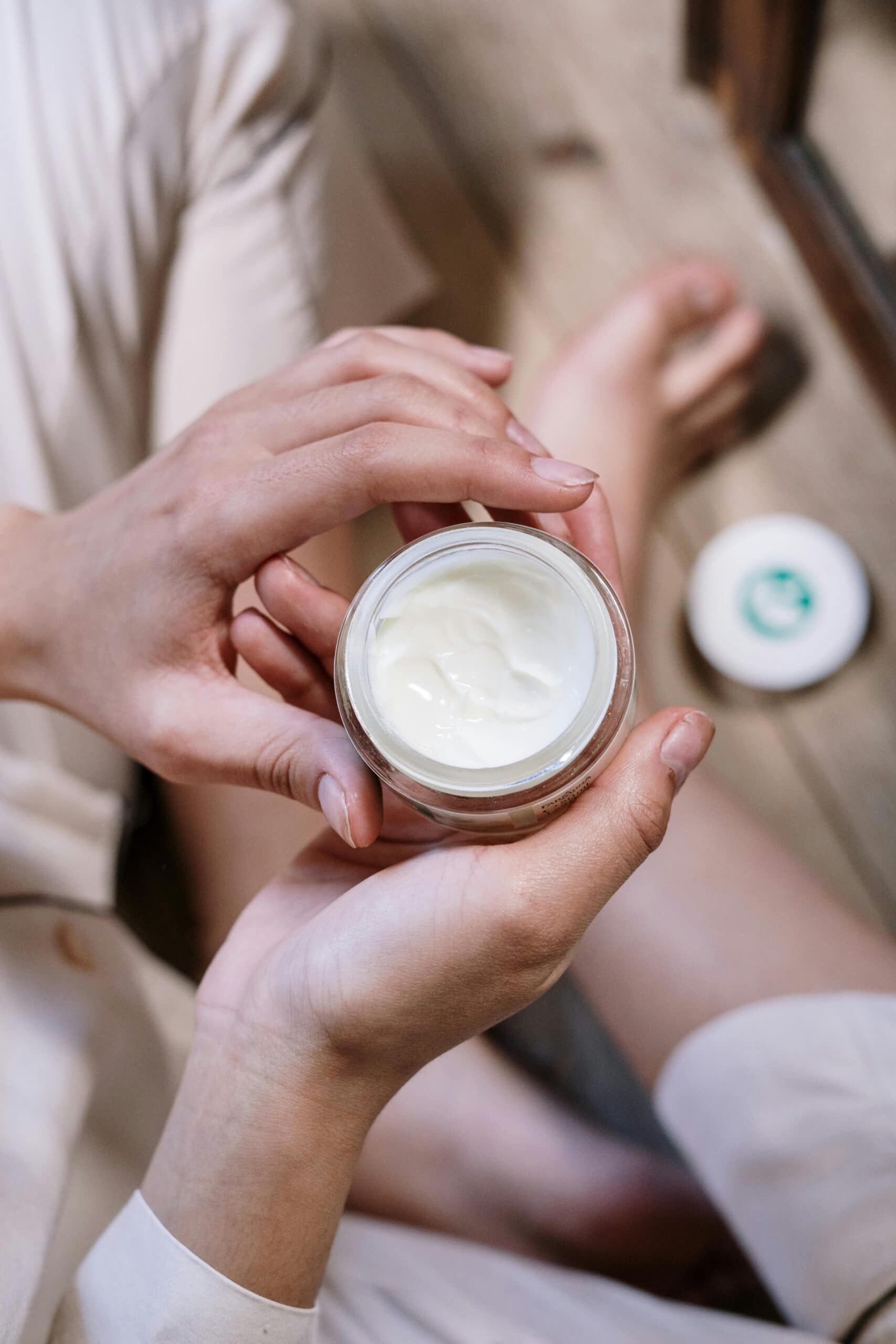 A hand holding a skincare cream product.