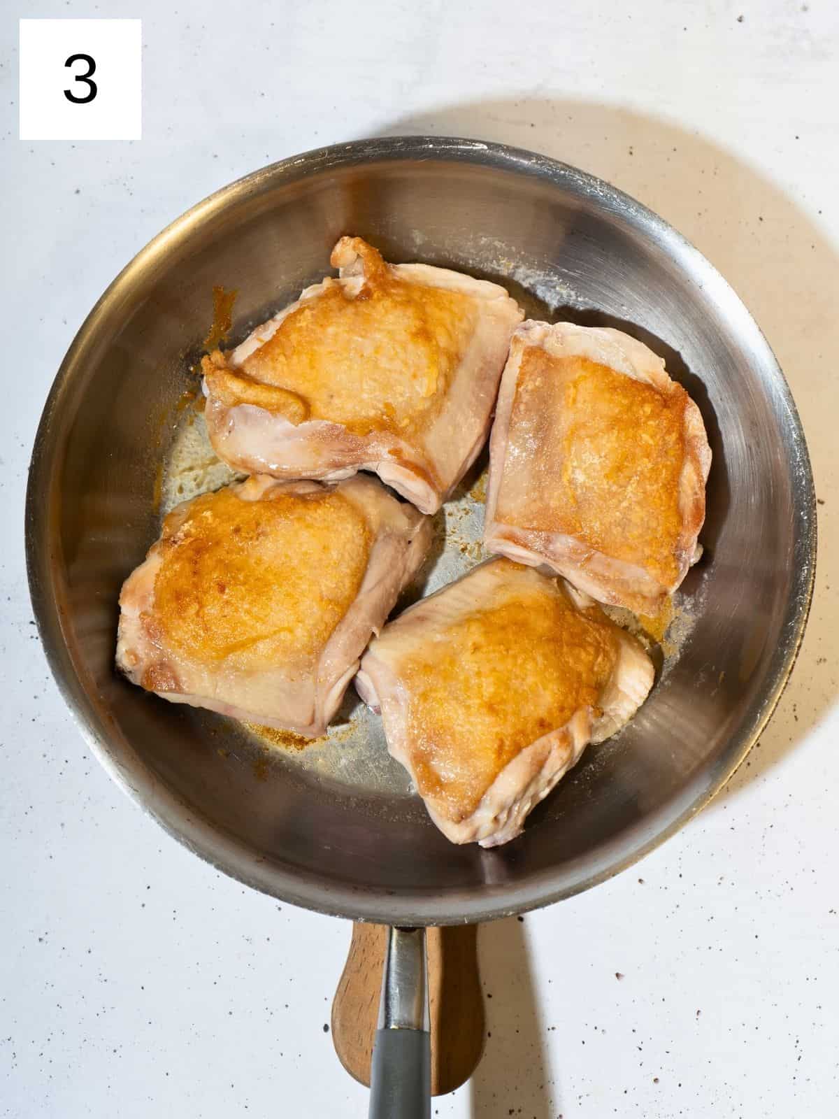 Searing chicken thighs in a pan.