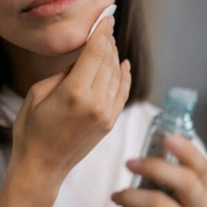 person putting toner on her face.