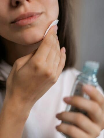 person putting toner on her face.