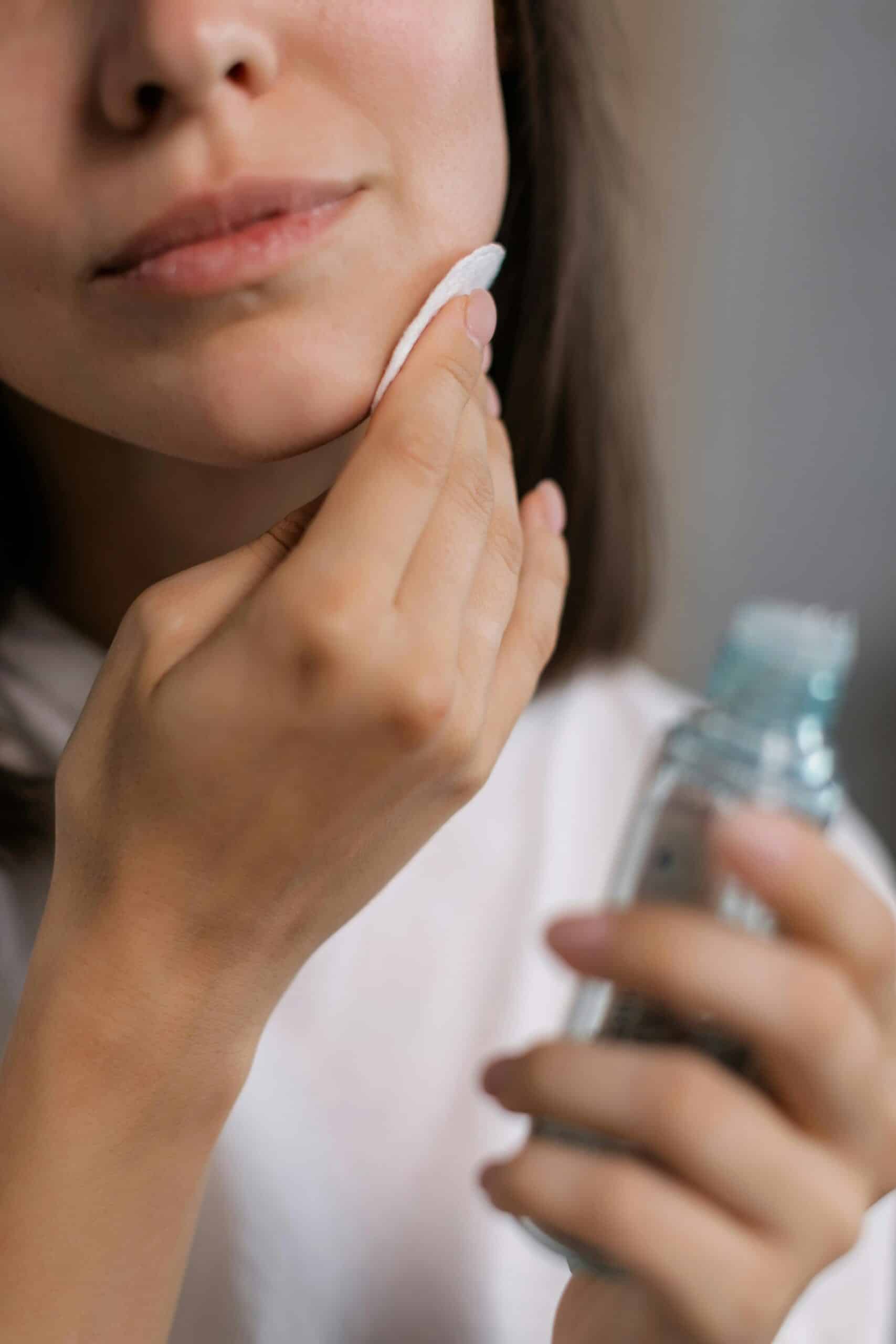 person putting toner on her face.