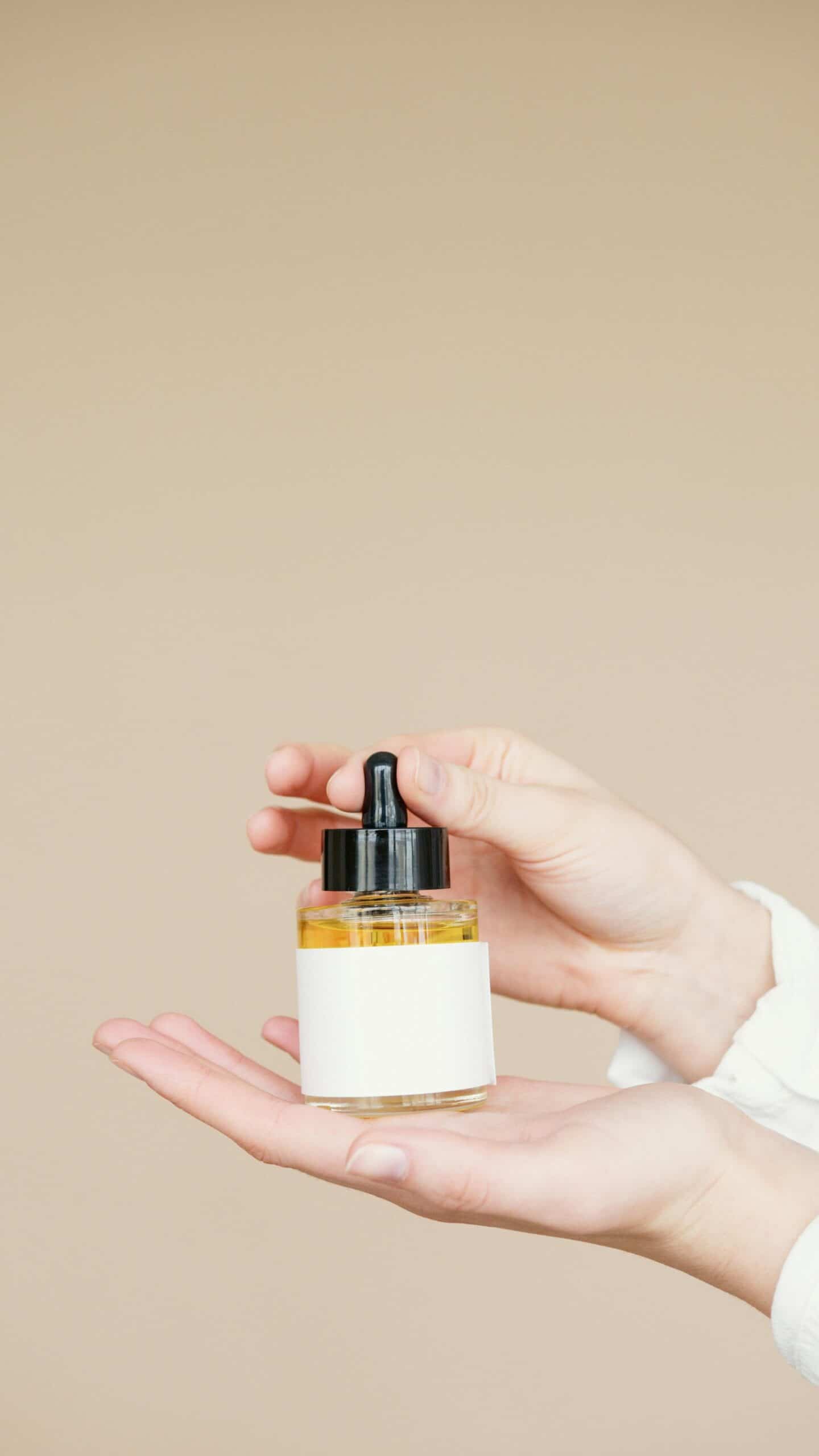 A bottle of serum placed on a person's palm. 