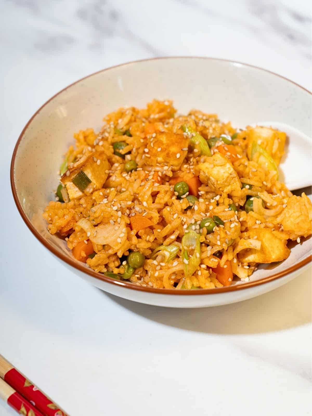 Savory gochujang fried rice with an assortment of vegetables and tofu, beautifully arranged on a plate, ready to be enjoyed.