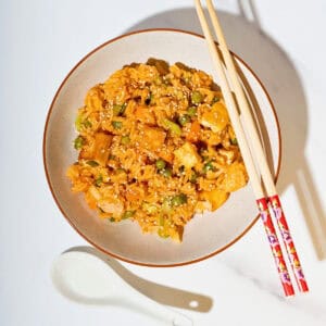 Delicious gochujang fried rice topped with colorful vegetables and cubed tofu, served on a plate, showcasing its vibrant colors and savory appeal.