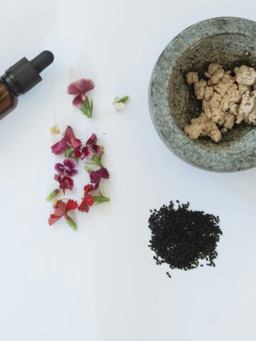 A flat lay of Korean acne-prone routine products, including herbal extracts, floral skincare, and a serum dropper, all on a clean white background.