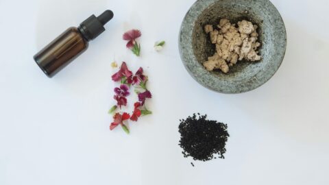 A flat lay of Korean acne-prone routine products, including herbal extracts, floral skincare, and a serum dropper, all on a clean white background.