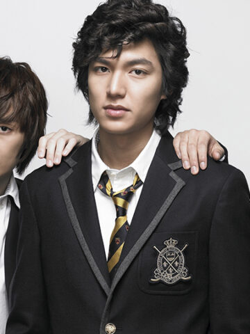 The four members of F4 from Boys Over Flowers wearing black school uniforms with striped ties, standing together with serious expressions against a white background.