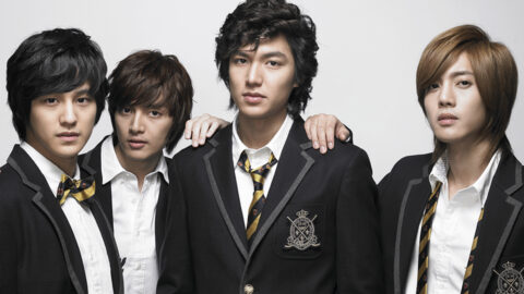 The four members of F4 from Boys Over Flowers wearing black school uniforms with striped ties, standing together with serious expressions against a white background.