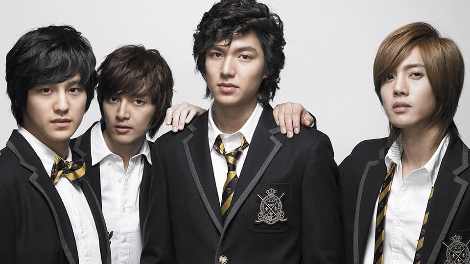 The four members of F4 from Boys Over Flowers wearing black school uniforms with striped ties, standing together with serious expressions against a white background.