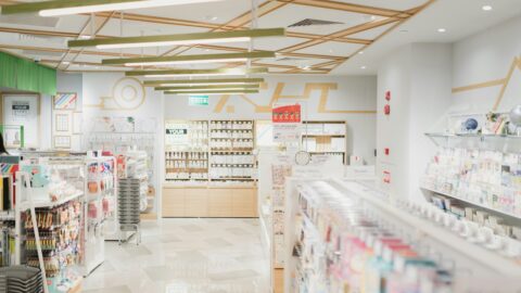 Wide-angle view of a well-lit modern drugstore, filled with skincare and personal care products on neatly organized shelves.