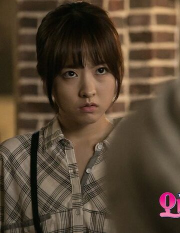 Young woman in plaid shirt looking serious in Seoul Korea Asia scene, brick background.
