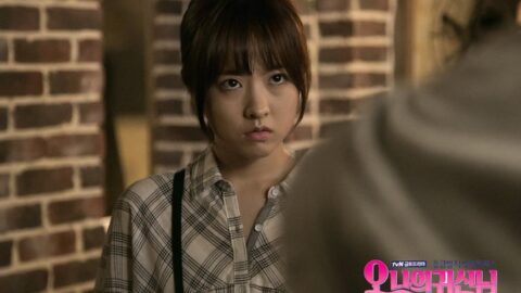 Young woman in plaid shirt looking serious in Seoul Korea Asia scene, brick background.