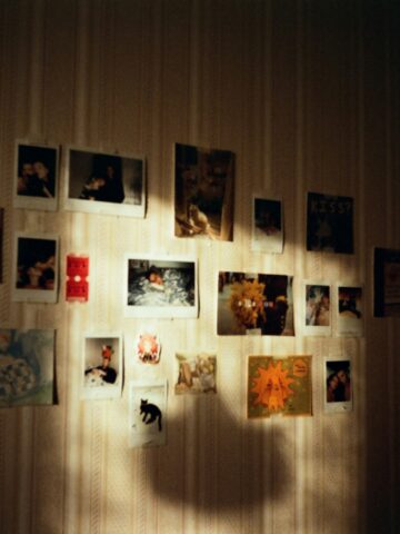 Colorful photo wall with Polaroid pictures and artwork inside a cozy Seoul cafe.